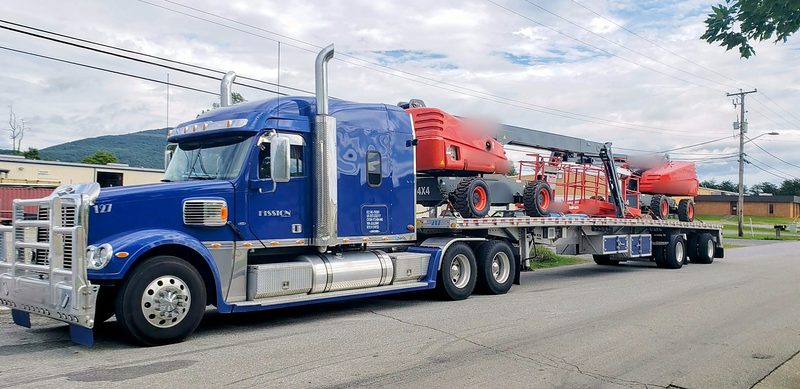 Two aerial boom lifts chained on a Fission flatbed