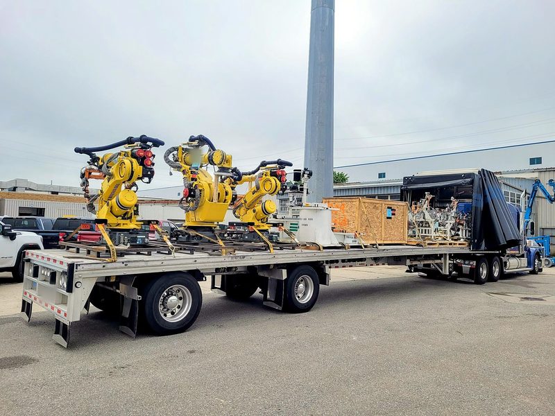 Industrial robots and crated tooling strapped on a Fission flatbed
